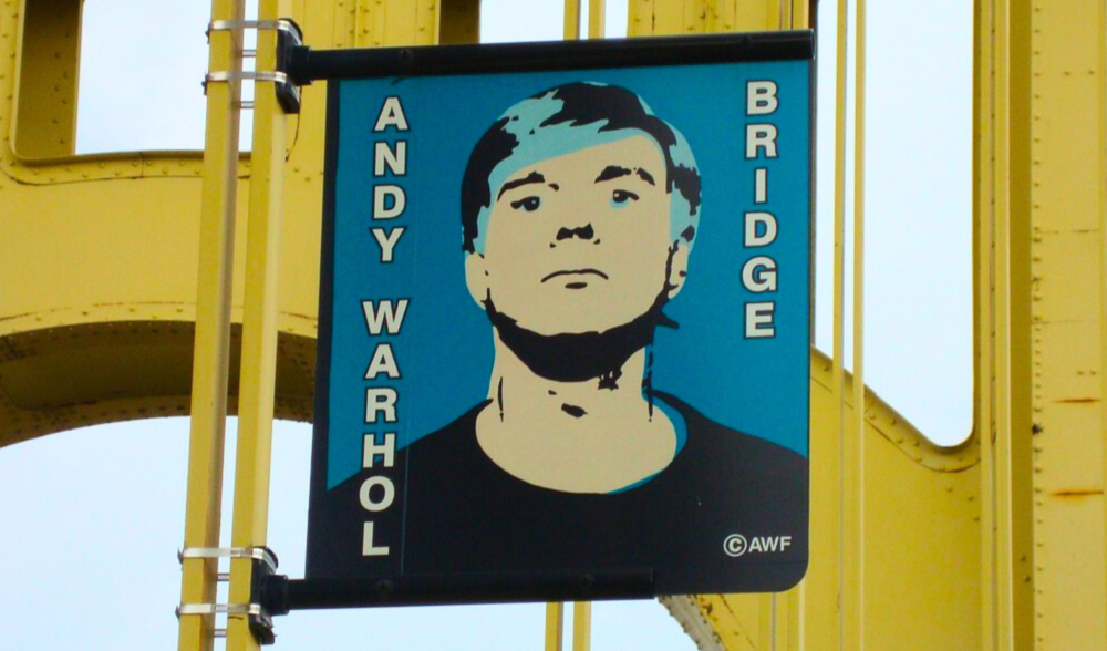 A large poster advertises one of Pittsburgh's famous gays, Andy Warhol, on the yellow bridge named after him.