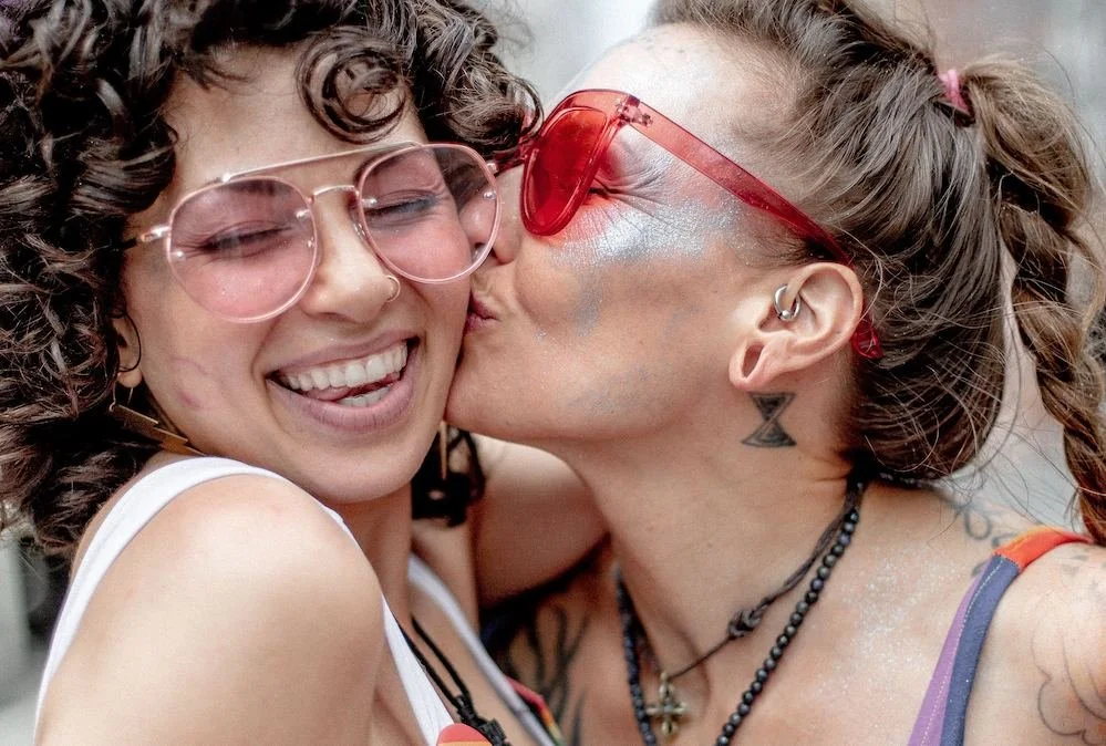 One woman kisses another's cheek as they celebrate gay pride in downtown Pittsburgh.
